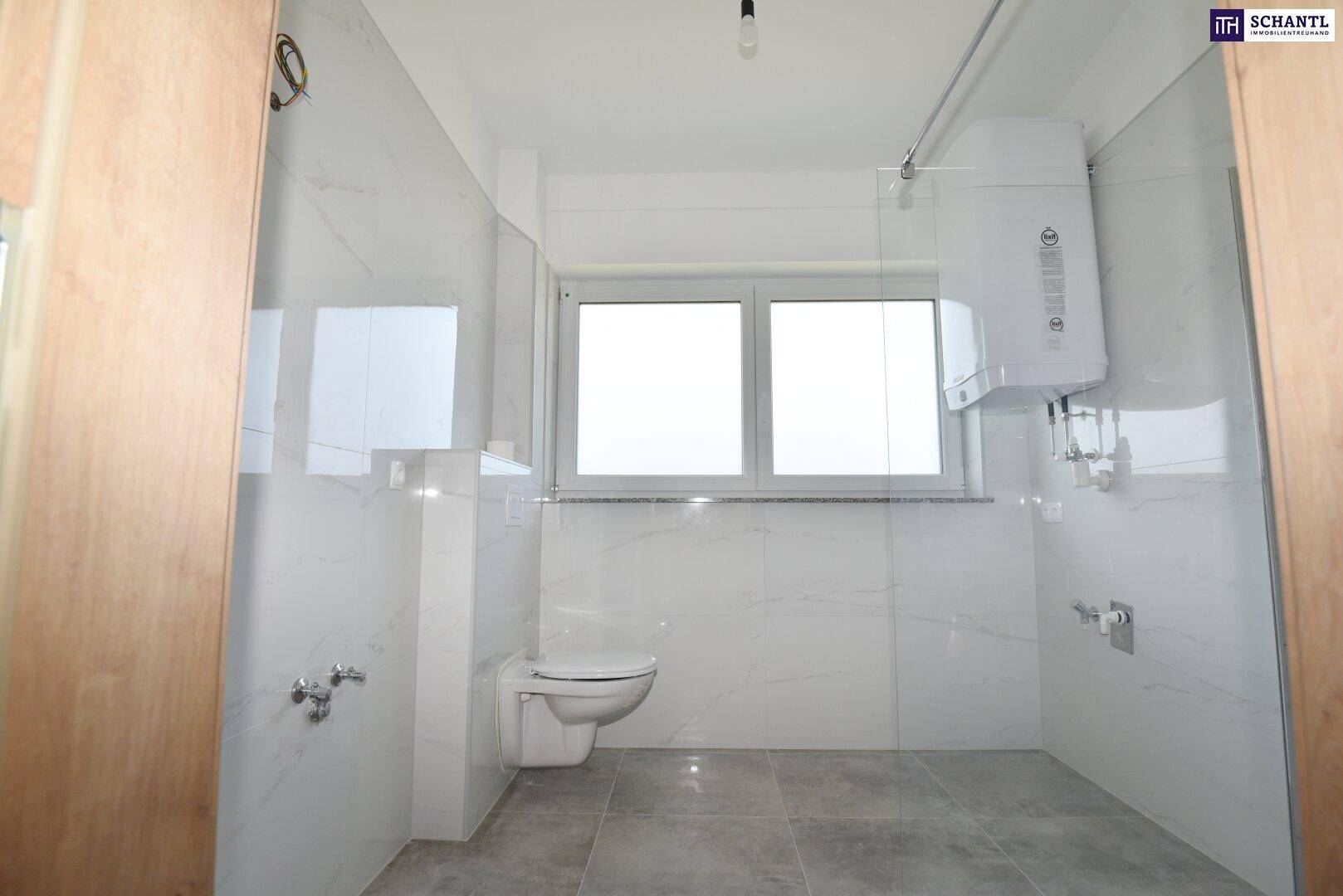 Helles Badezimmer mit Wand-WC und Fenster, bietet Platz für eine Dusche oder Badewanne.