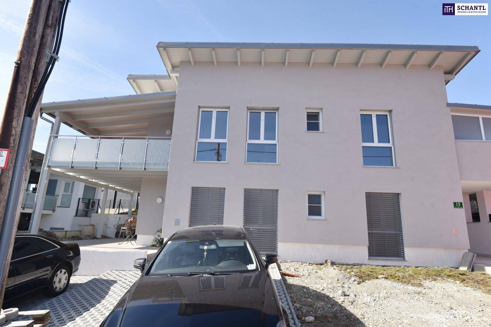 Modernes Mehrfamilienhaus mit heller Fassade, großen Fenstern und Außenparkplätzen.