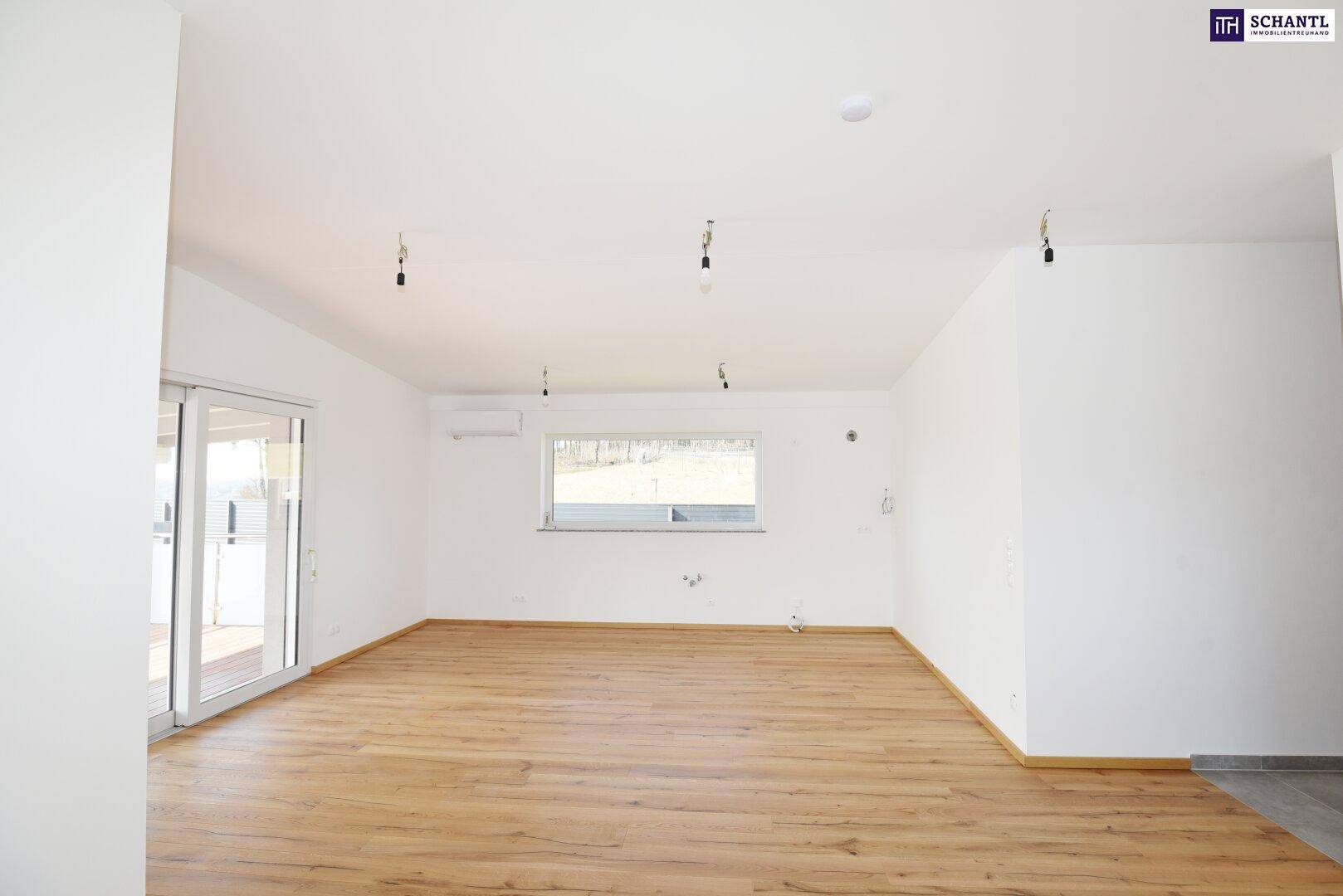 Helles Wohnzimmer mit Holzboden und großem Fenster, bietet viel Tageslicht und Ausblick.