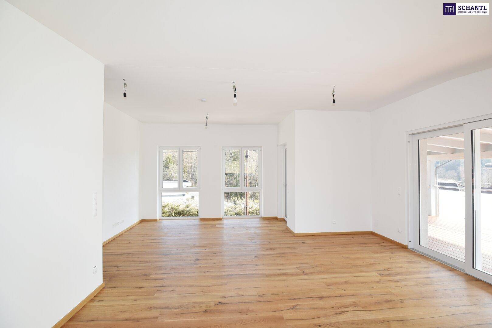 Großes, helles Wohnzimmer mit Holzboden und Zugang zu einem überdachten Balkon.