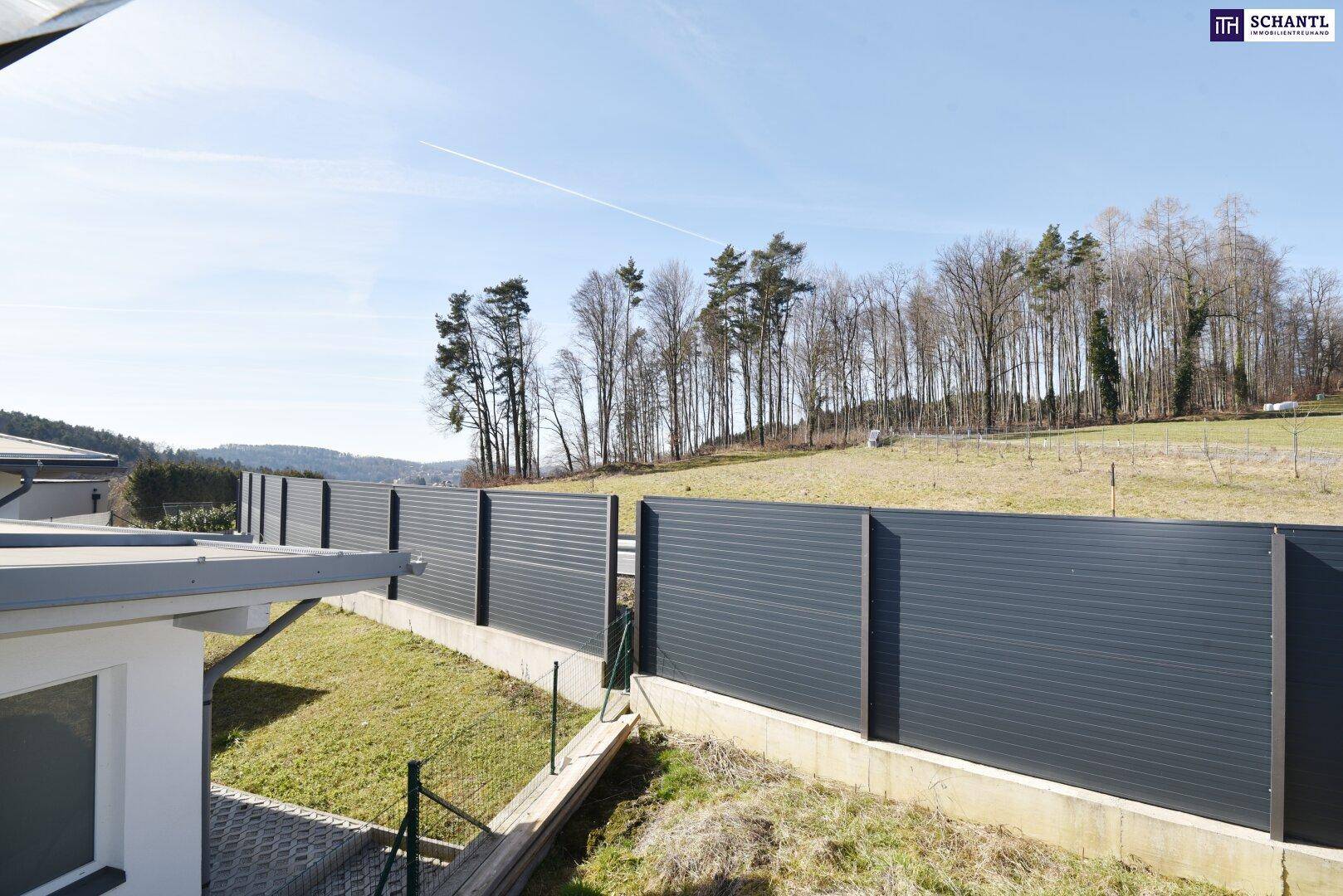 Weitläufiger Blick über eine moderne Zaunanlage auf die umliegende Natur und Waldgebiete.