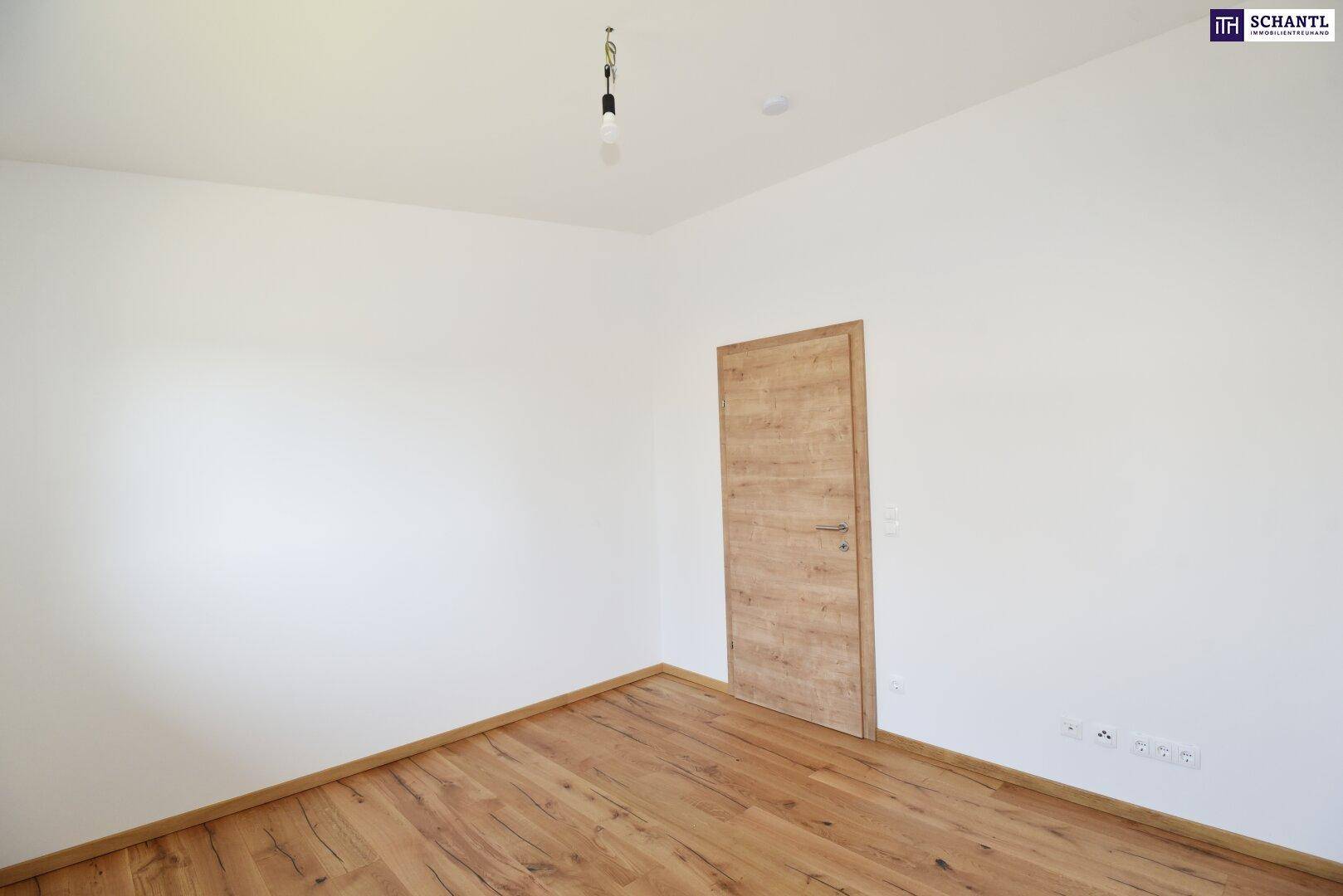 Leeres Schlafzimmer mit Holzboden und einer modernen Holztür, bereit zur individuellen Gestaltung.