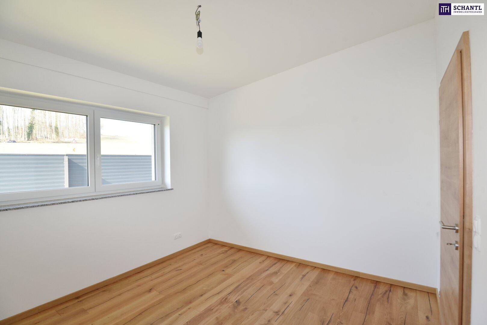 Leeres Schlafzimmer mit Holzboden und Fenster, ausgestattet mit einem Rollladen für Privatsphäre.