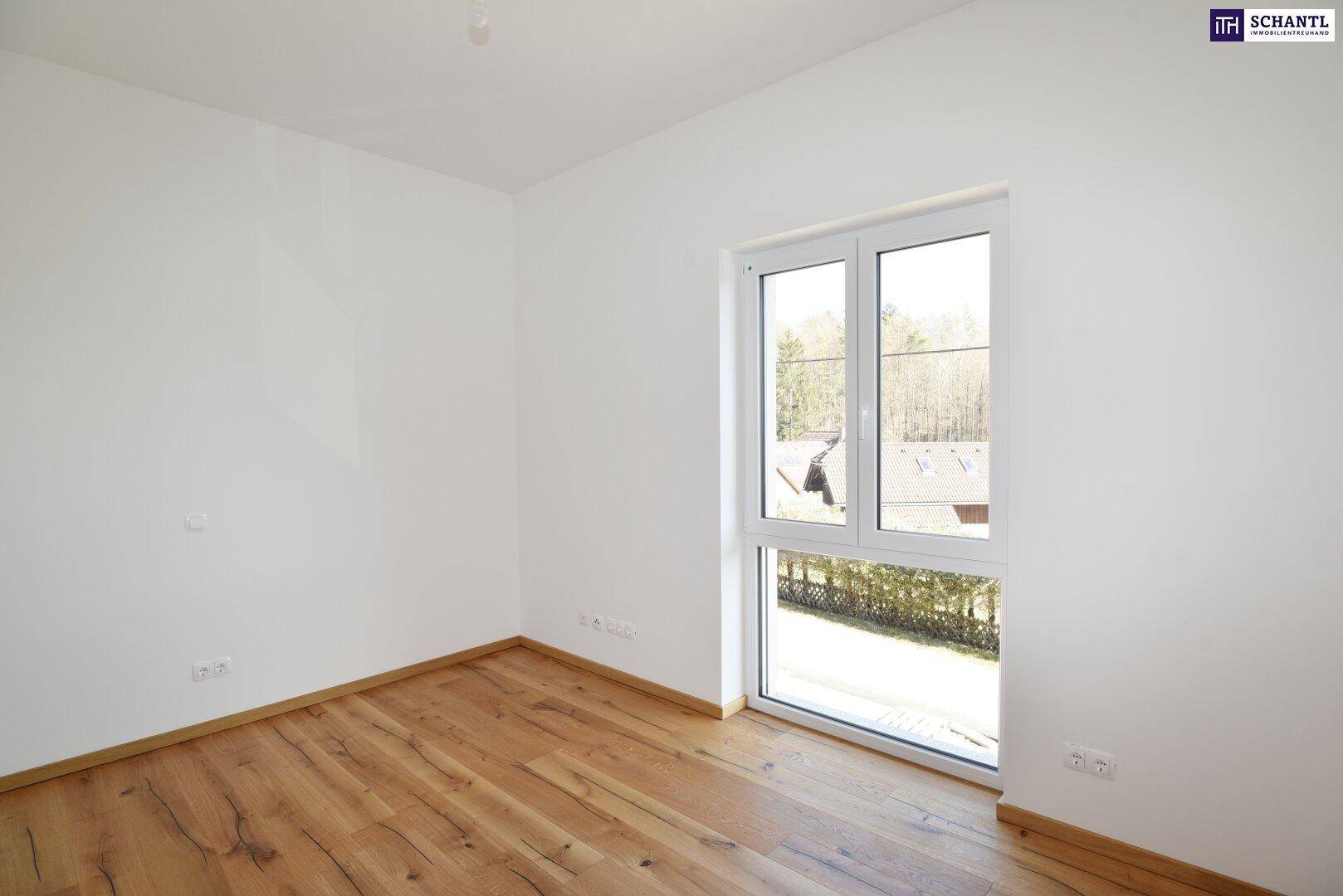 Leeres Schlafzimmer mit Holzboden und Fenster, das einen weiten Blick in die Umgebung bietet.