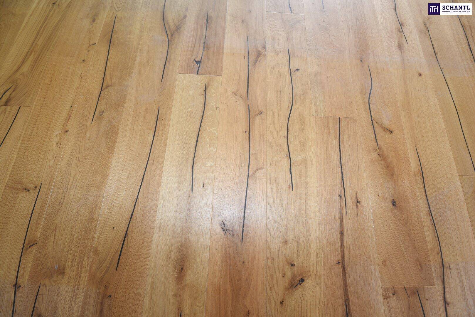 Nahaufnahme eines hochwertigen Holzbodens mit charakteristischer Maserung und dunklen Akzenten.
