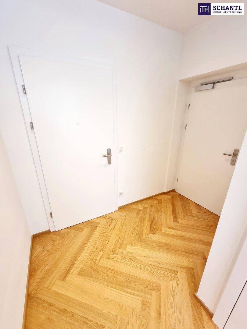 Heller Flur mit zwei weißen Türen und neuem Fischgrätparkettboden.