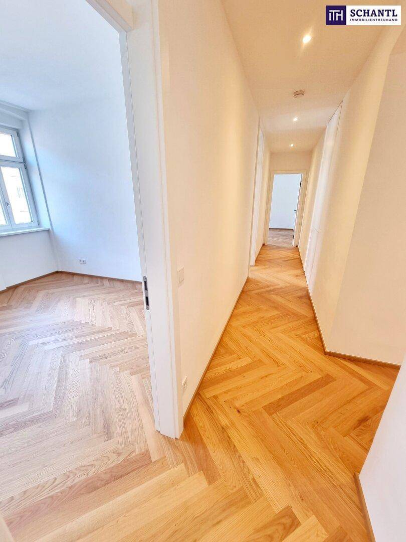 Blick vom Zimmer in den hellen Flur mit Fischgrätparkettboden.