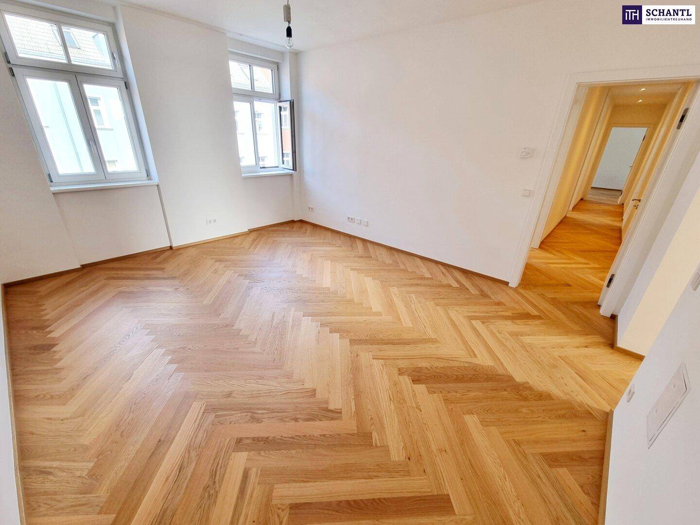 Helles Zimmer mit Fischgrätparkettboden und Zugang zum Flur.