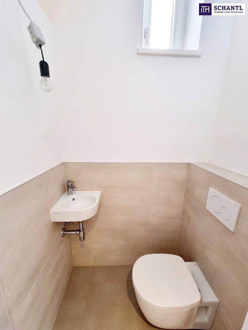 Modernes Gäste-WC mit wandhängender Toilette, kleinem Waschbecken und Fenster.