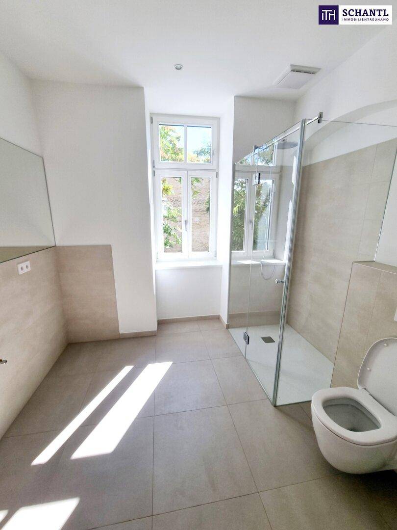 Modernes Badezimmer mit ebenerdiger Dusche, Toilette und Fenster für Tageslicht.