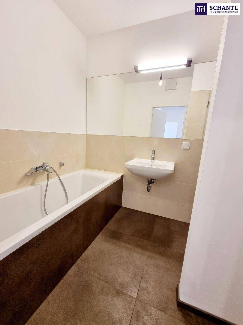 Helles Badezimmer mit Badewanne, Waschbecken und großem Spiegel.