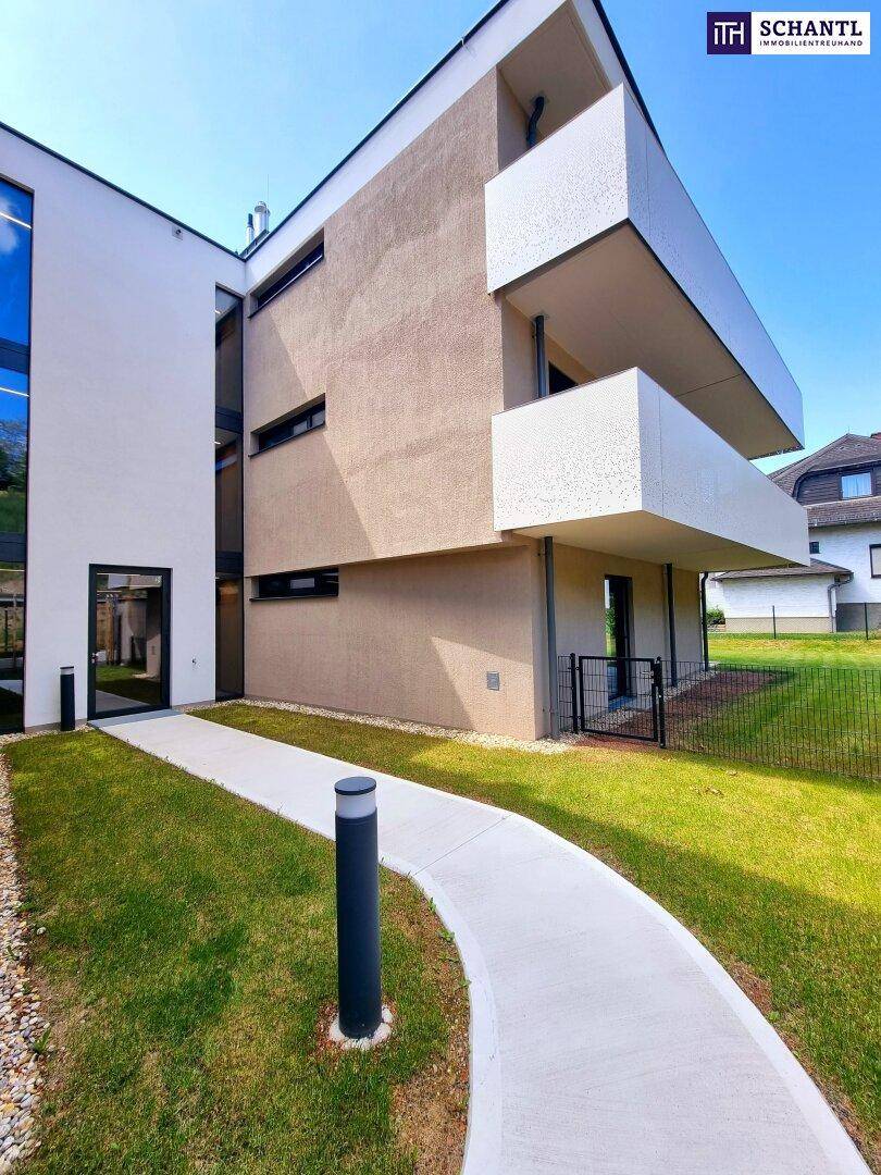 Seitenansicht des modernen Gebäudes mit gepflegtem Rasen und einem geschwungenen Gehweg an einem sonnigen Tag.