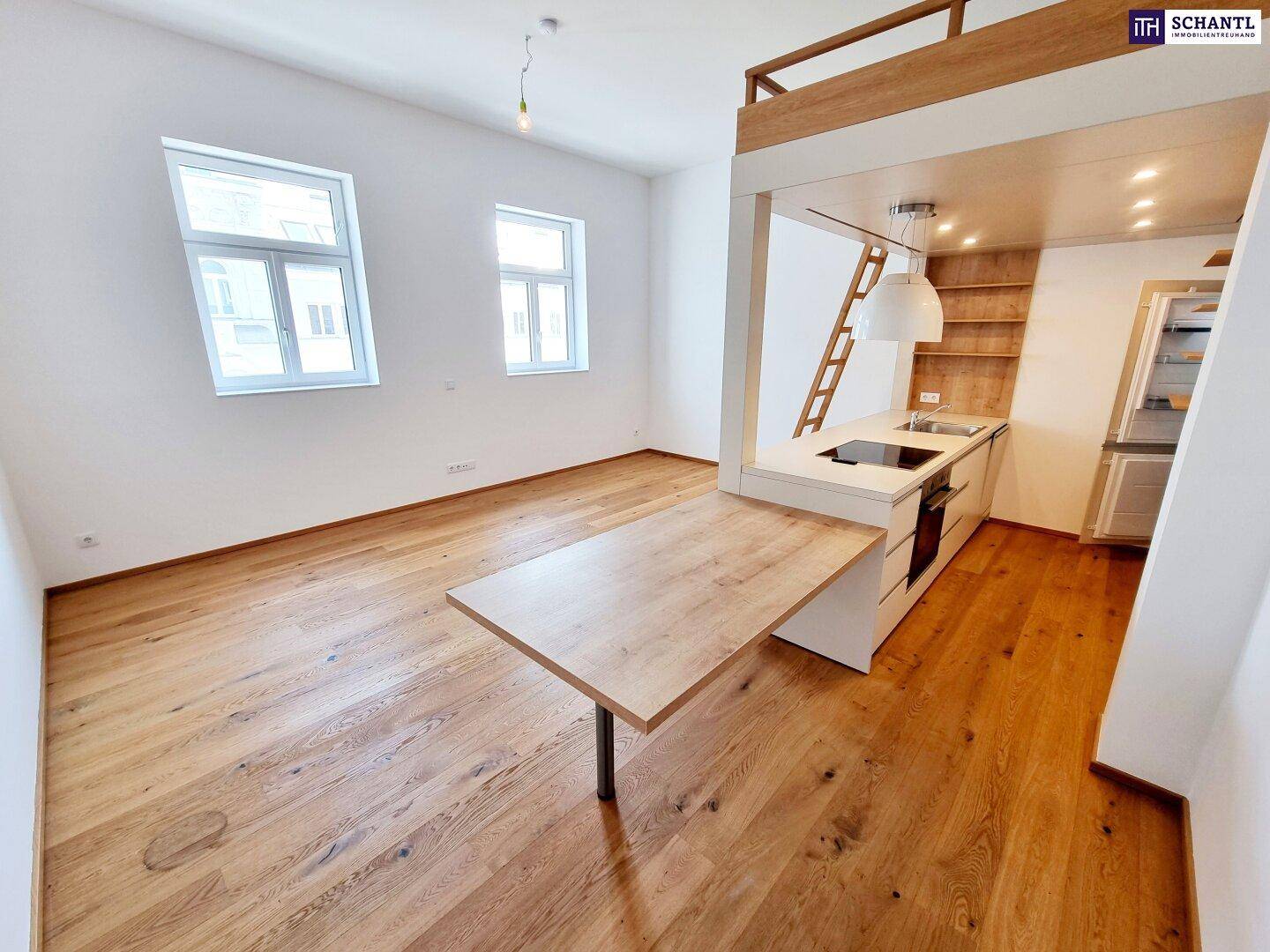 Lichtdurchflutetes Wohnzimmer mit Holzboden, integrierter Küchenzeile und Blick nach draußen.