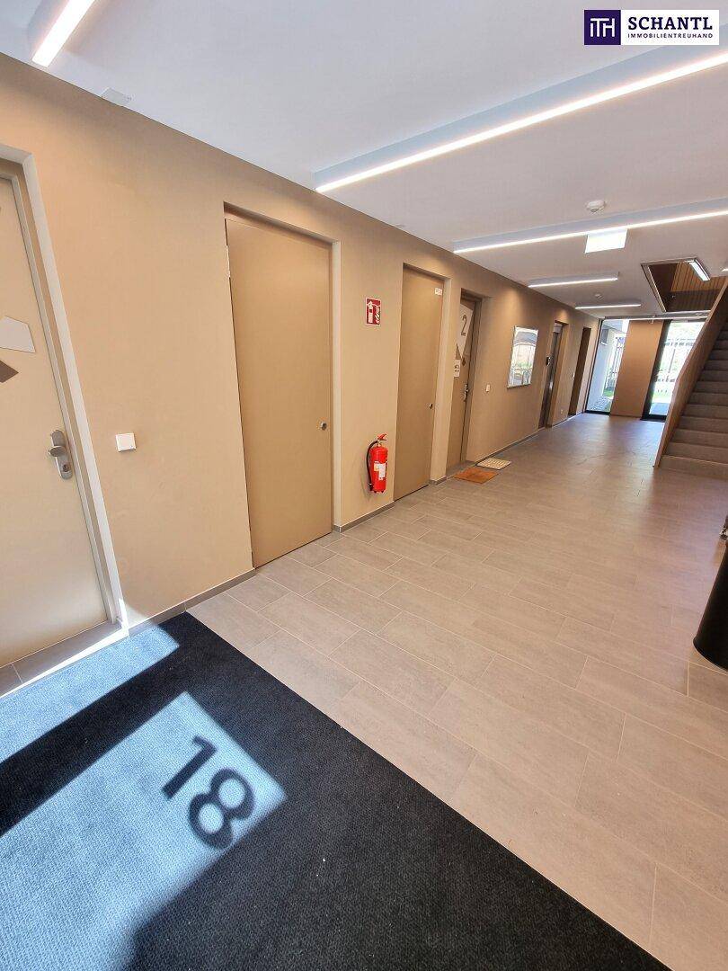 Moderner Flur mit hellen Türen, Fliesenboden und einer Fußmatte mit Nummer 18 in einem Neubau.