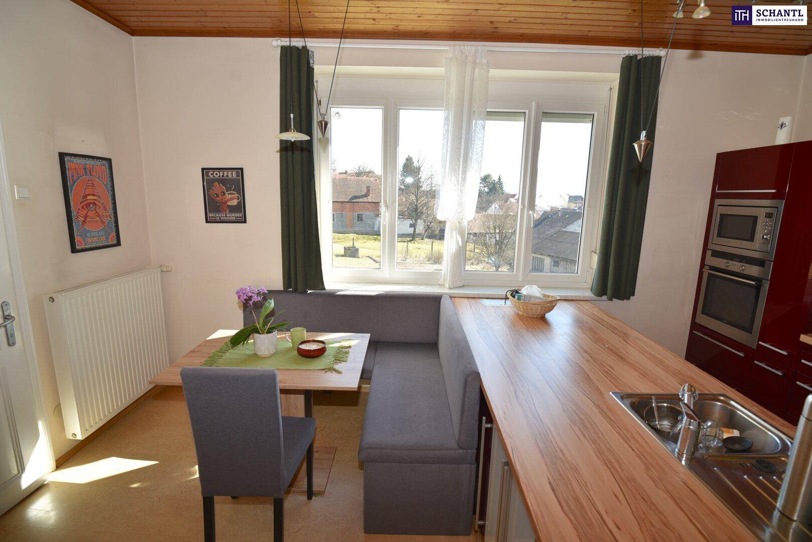 Helle Küche mit Essecke, Holzbalkendecke und großem Fenster für viel Tageslicht.