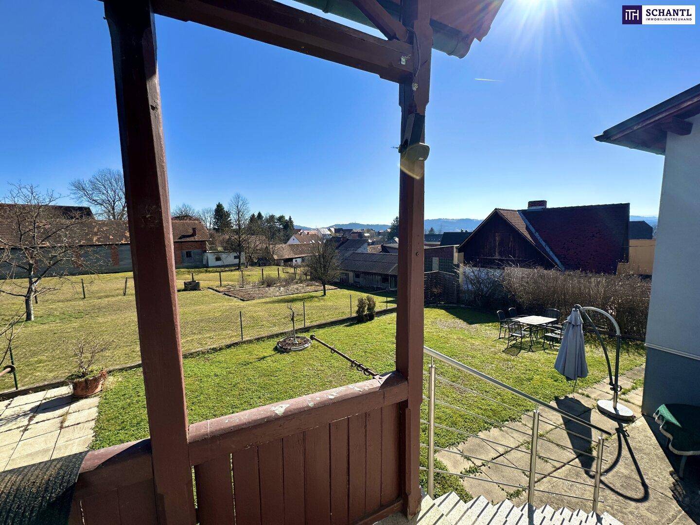 Blick von der Veranda auf den weitläufigen Garten und die umliegende Landschaft.