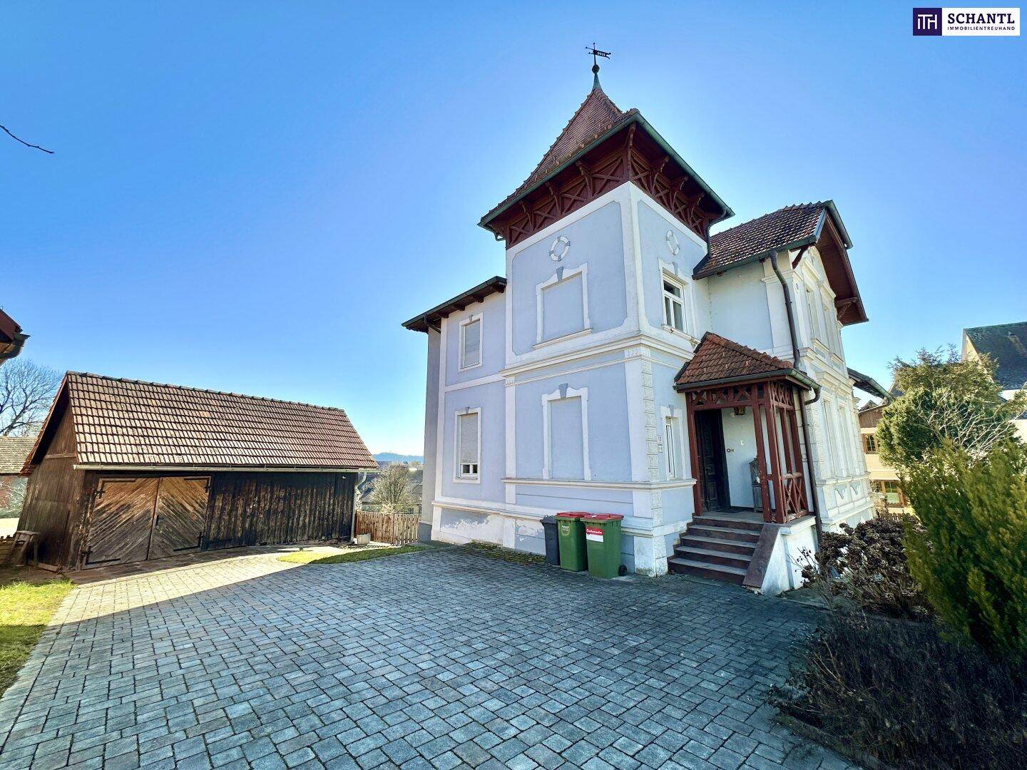 Historisches Gebäude mit gepflasterter Auffahrt und angrenzender Scheune.