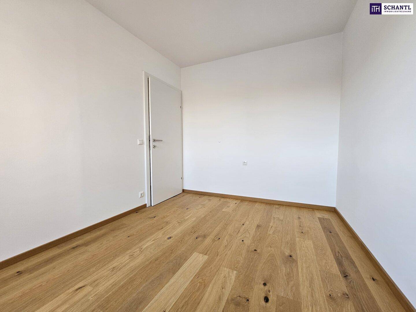 Leeres Zimmer mit hellem Parkettboden und weißen Wänden, bereit zum Einrichten.
