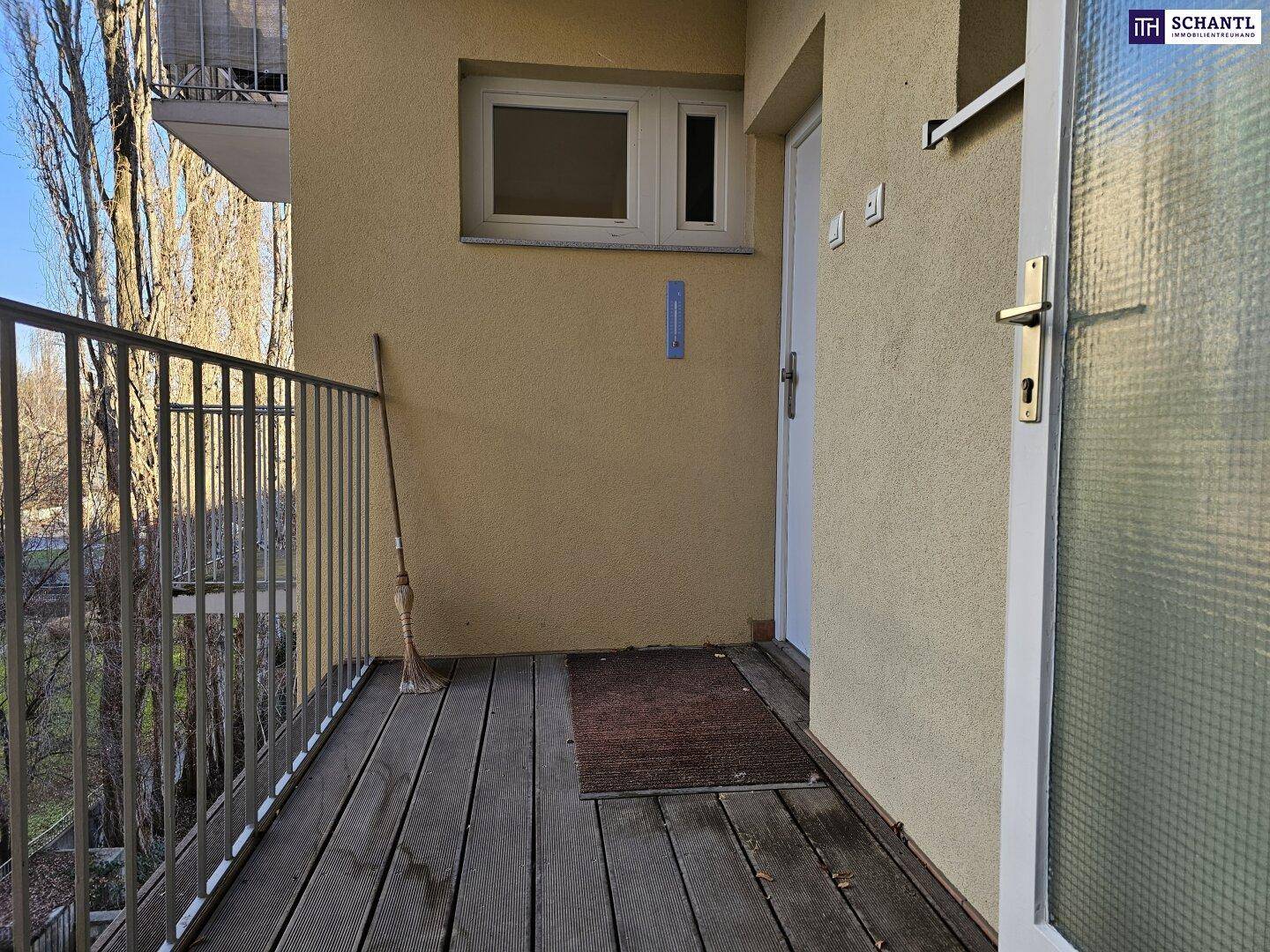 Kleiner Balkon mit Holzboden und Metallgeländer, ideal für eine kleine Sitzecke.