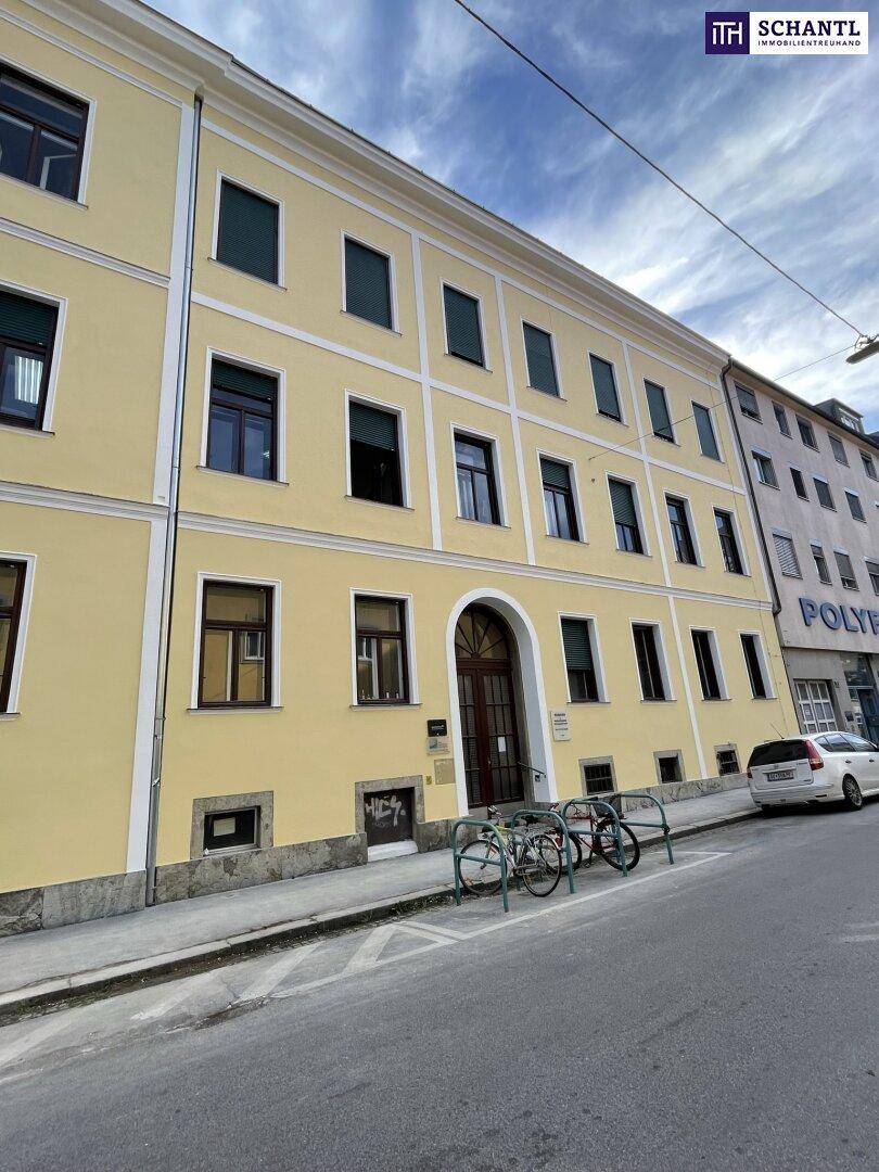 Fassade eines gelben Mehrfamilienhauses mit vielen Fenstern und einem Eingangsbereich.