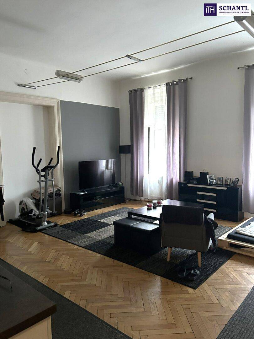 Geräumiges Wohnzimmer mit Parkettboden, großem Fernseher und Fitnessgerät.