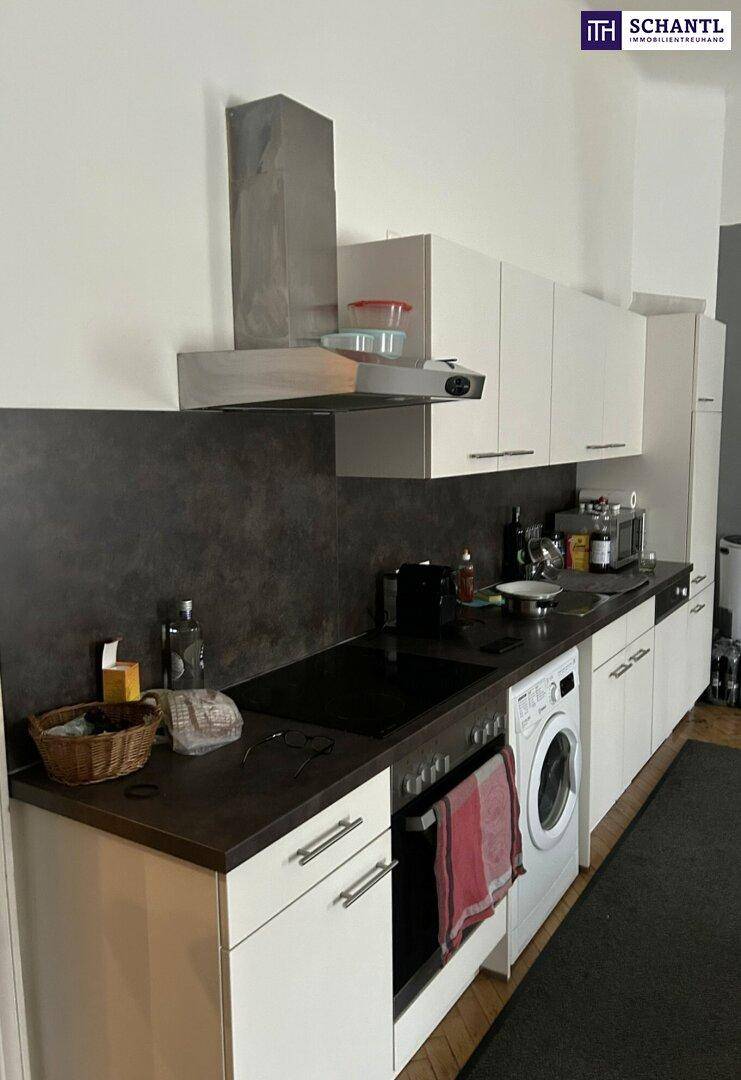 Funktionale Küche mit weißen Schränken, dunkler Arbeitsplatte und integriertem Backofen.