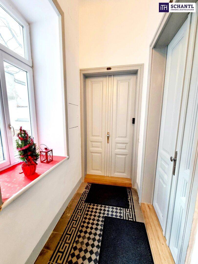 Heller Eingangsbereich mit Holzboden, hohen Türen und Fenster zur Straße.