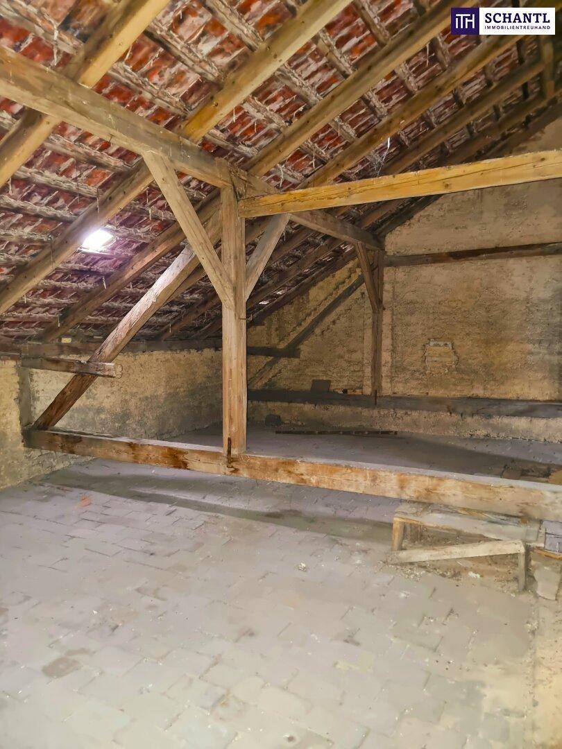 Großer Dachboden mit Holzbalken und Ziegeln, ideal für zukünftigen Ausbau.
