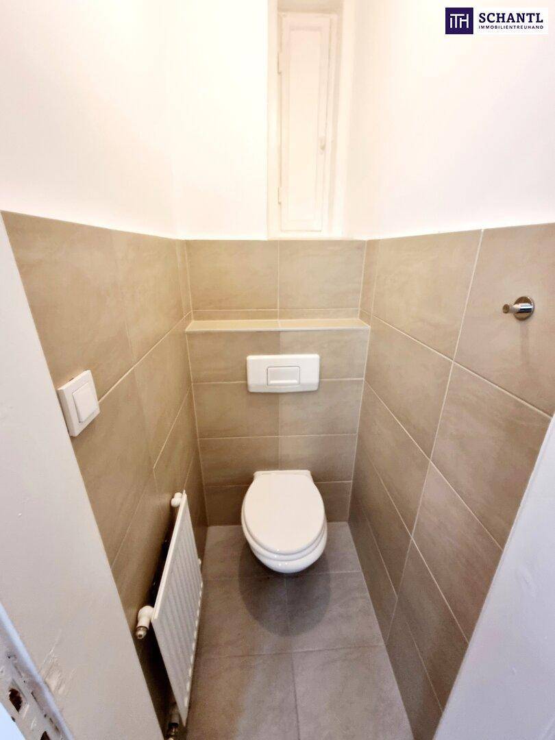 Kleines, separates WC mit wandmontierter Toilette und beigefarbenen Fliesen.