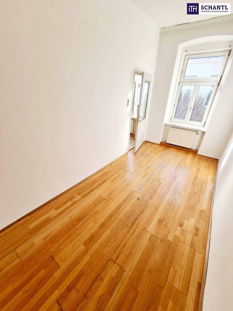Langer, schmaler Raum mit Holzboden, weißen Wänden und einem Fenster, das Sonnenlicht einfängt.