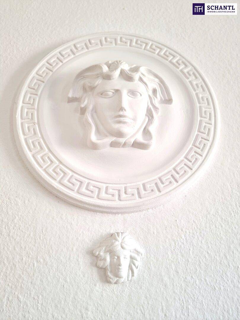 Dekorative Stuckelemente an einer weißen Wand, die einen klassischen Stil andeuten.