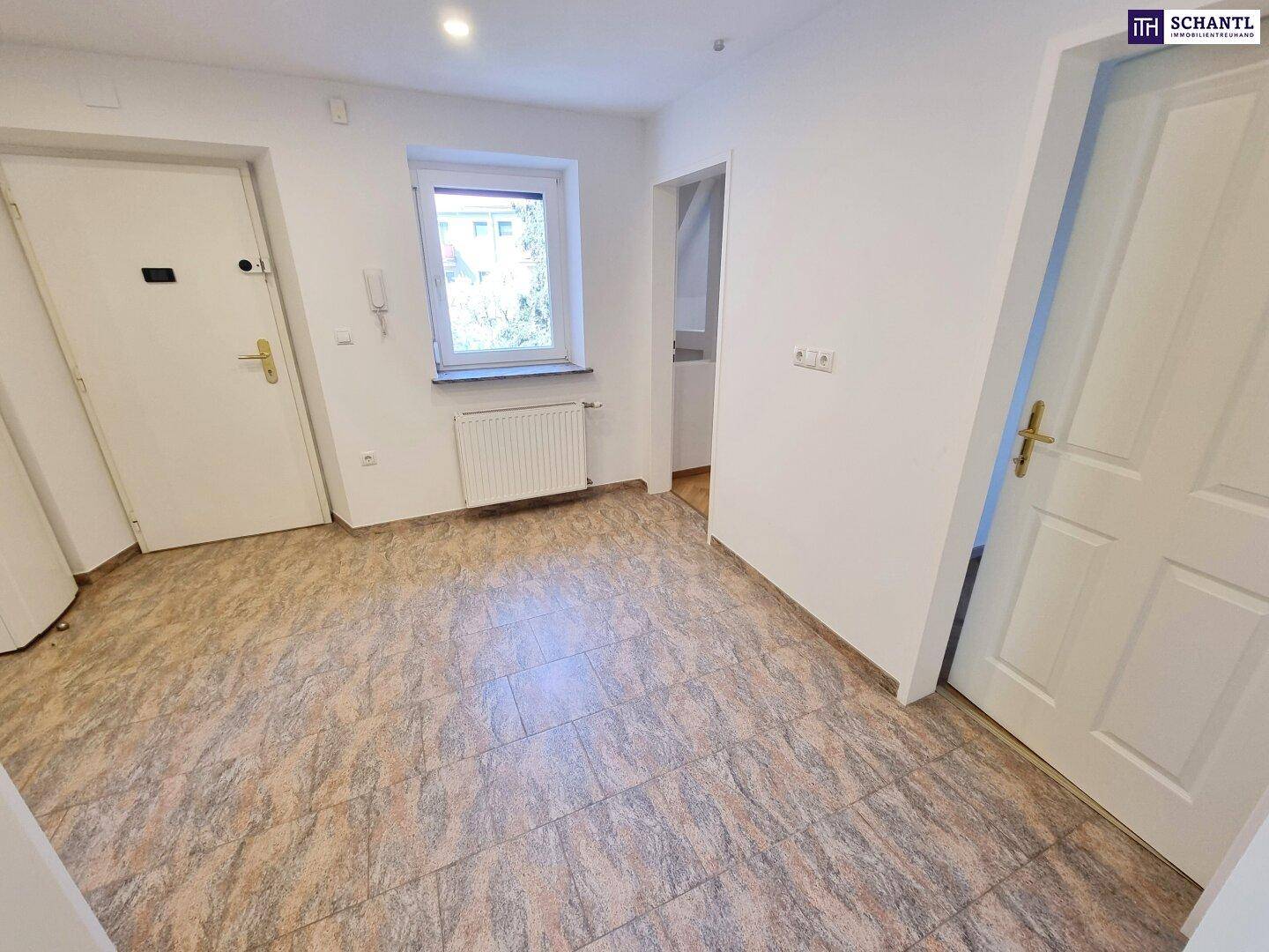 Heller Flur mit Fliesenboden, Fenster und Gegensprechanlage.