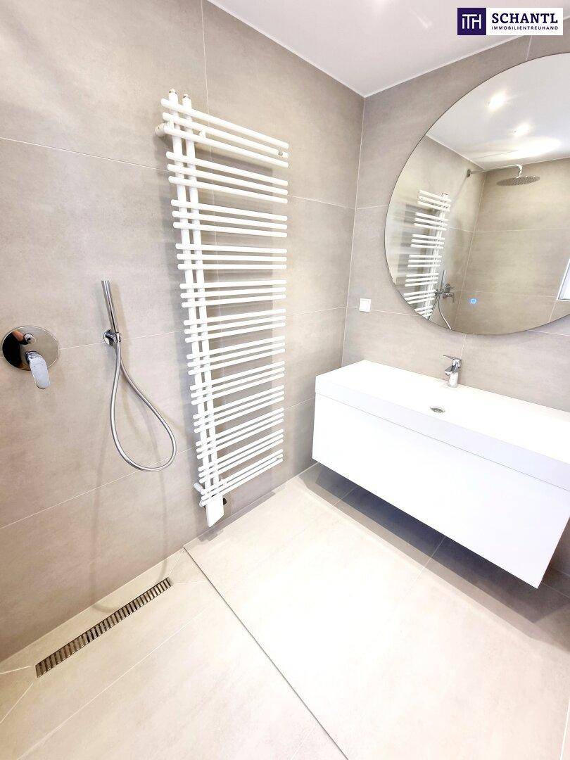 Modernes Badezimmer mit ebenerdiger Dusche, Waschtisch und beheiztem Handtuchhalter.