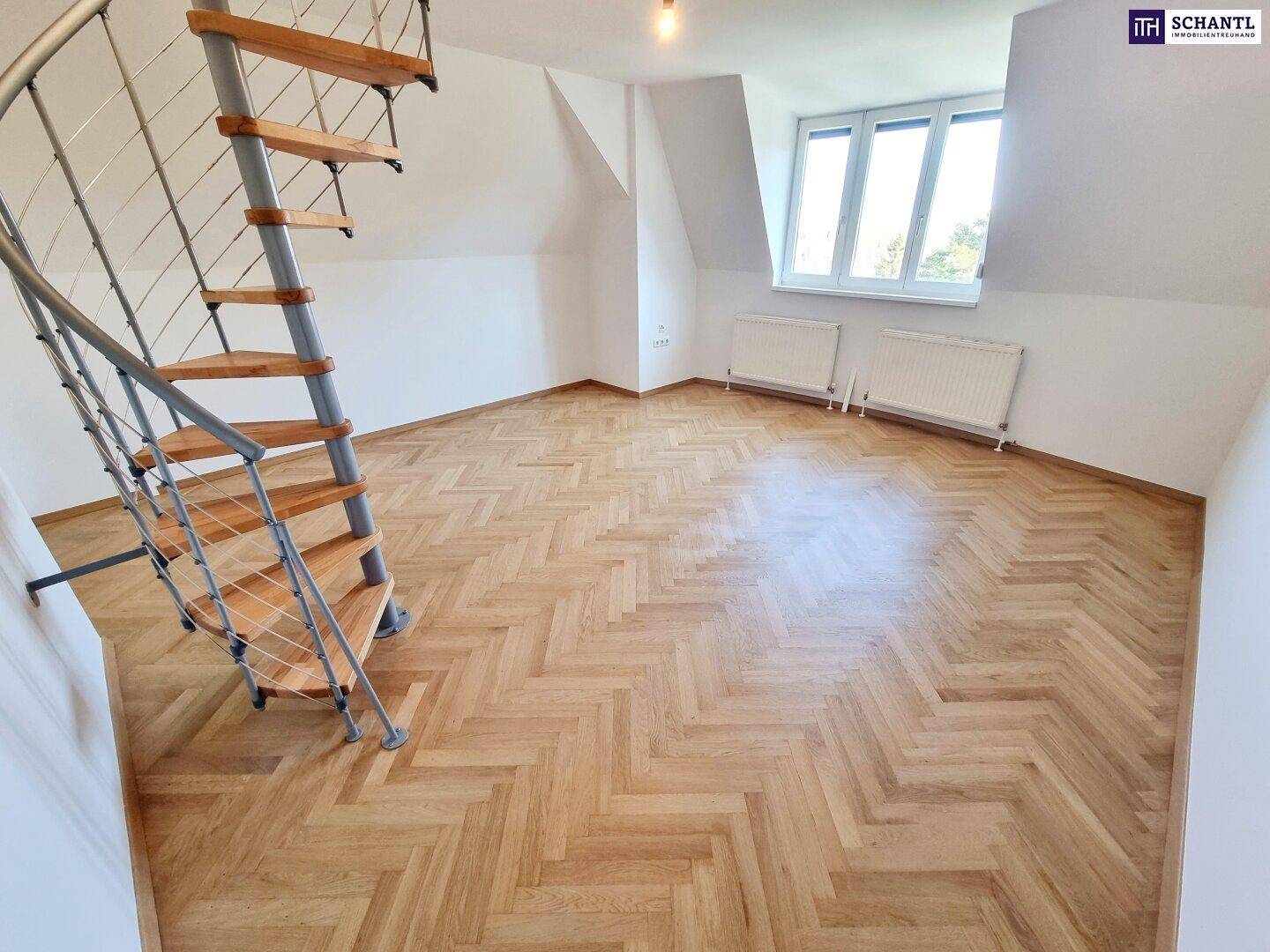 Dachgeschossraum mit Fischgrätparkett und Wendeltreppe zu einer oberen Ebene.