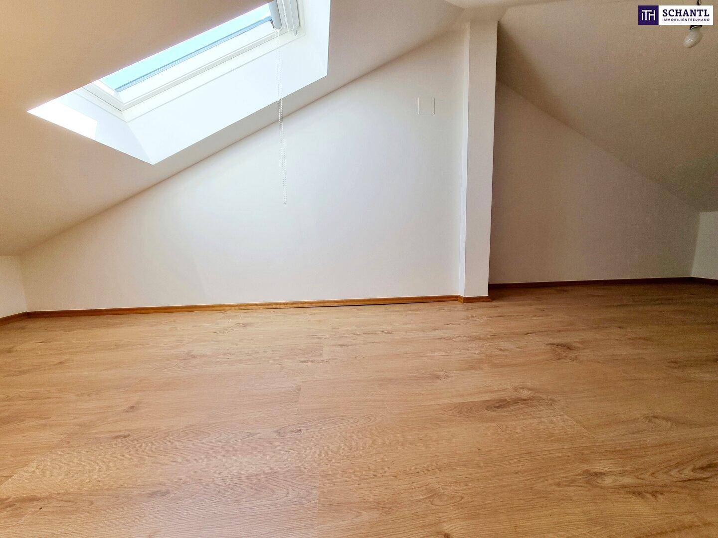 Heller Dachgeschossraum mit Laminatboden und großem Dachfenster für natürliches Licht.