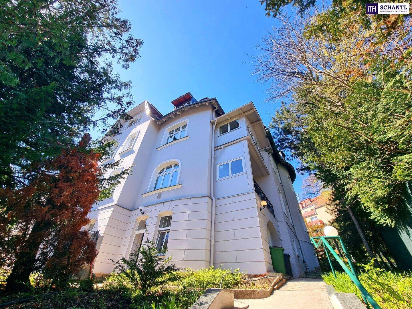 Seitenansicht eines historischen Gebäudes mit gepflegter Fassade und Grünflächen.