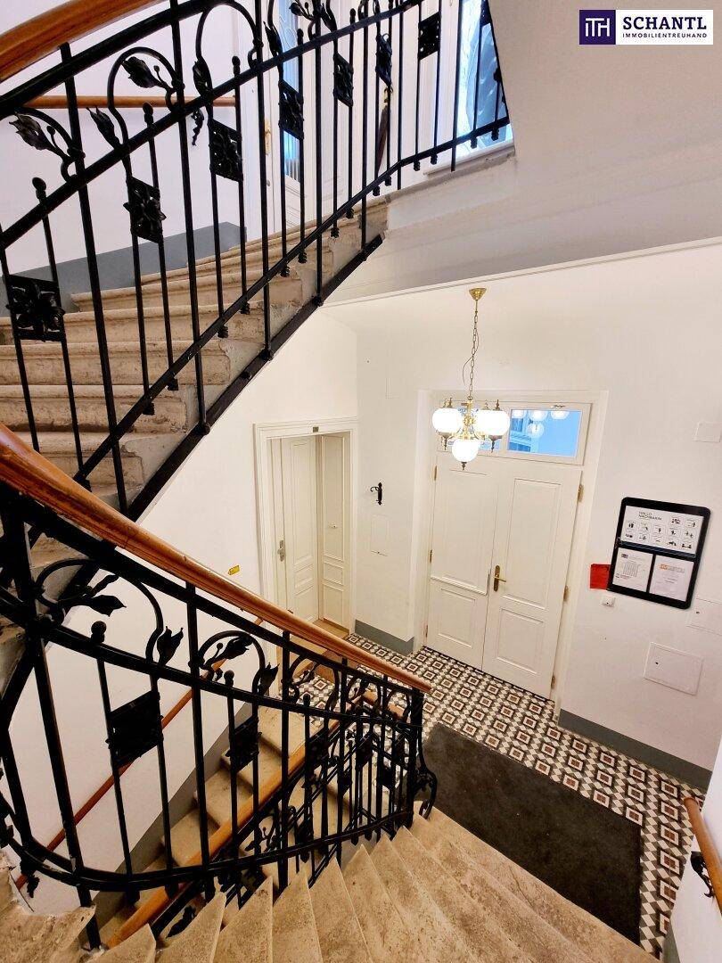 Elegantes Treppenhaus mit Steinstufen, kunstvollem Geländer und gemusterten Fliesen.