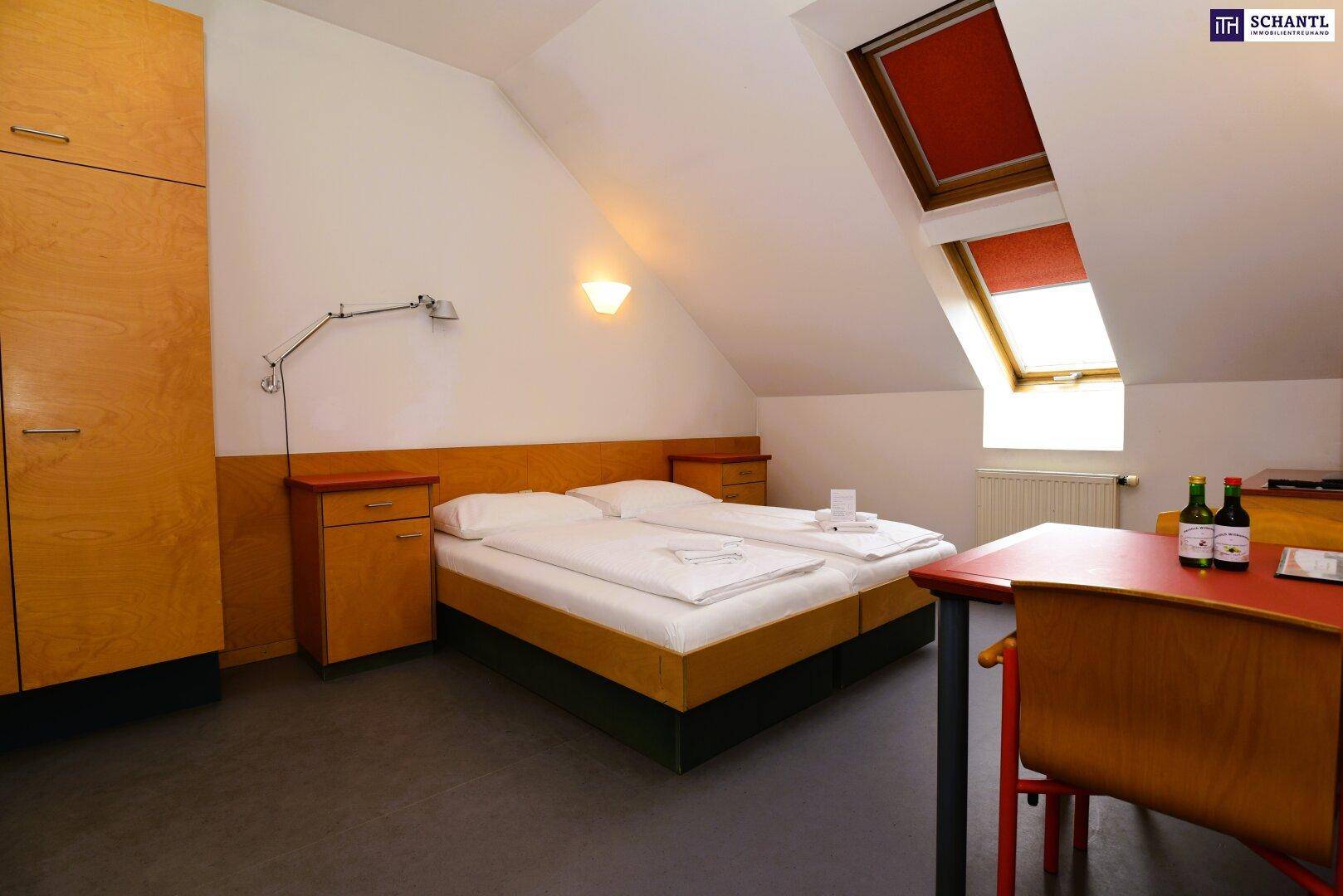 Gemütliches Schlafzimmer im Dachgeschoss mit Schrägen, Einzelbetten und Dachfenstern.