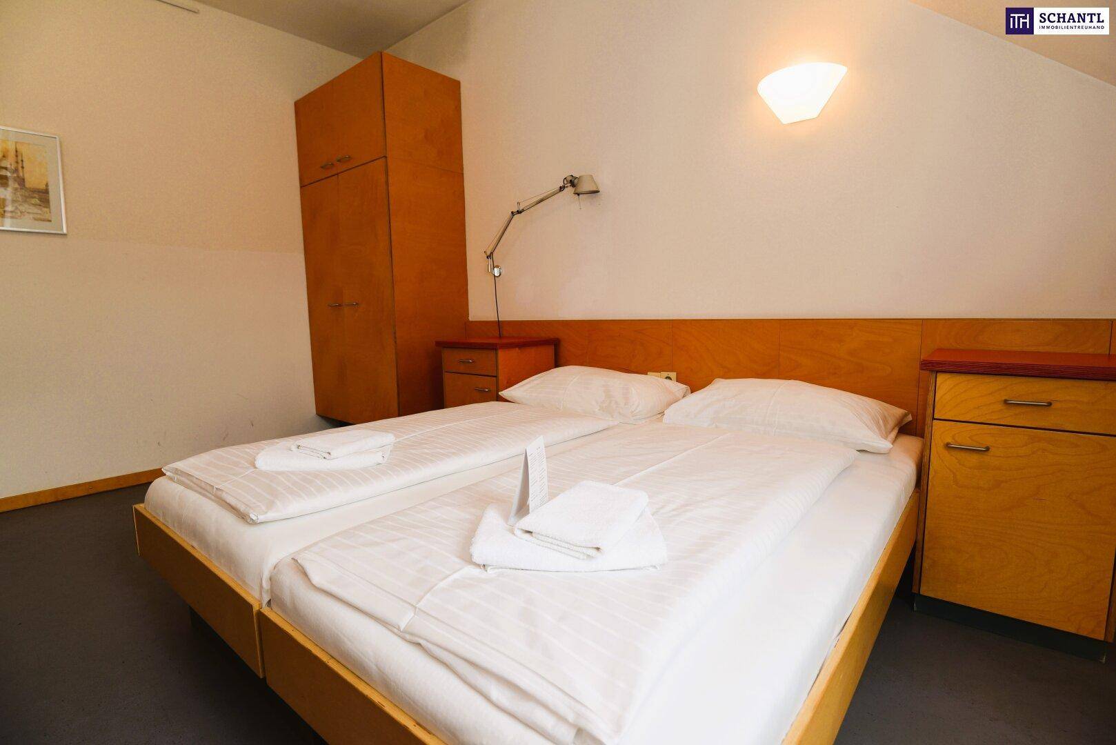 Nahaufnahme der Betten in einem Dachgeschoss-Schlafzimmer mit einfacher Einrichtung.