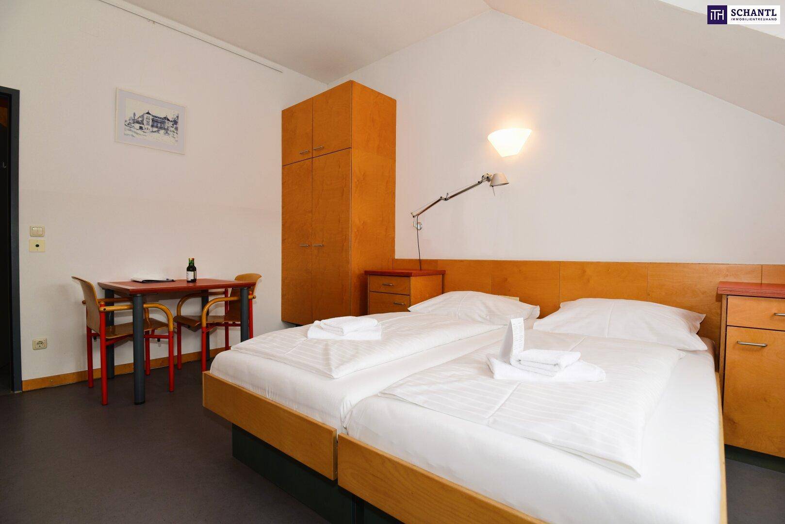 Schlafzimmer im Dachgeschoss mit Holzmöbeln, zwei Betten und schrägen Wänden.