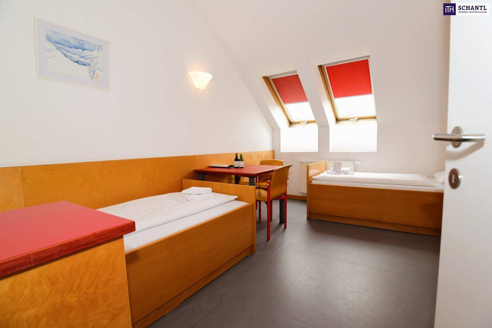 Dachgeschoss-Schlafzimmer mit zwei Einzelbetten, Schreibtisch und zwei Dachfenstern.