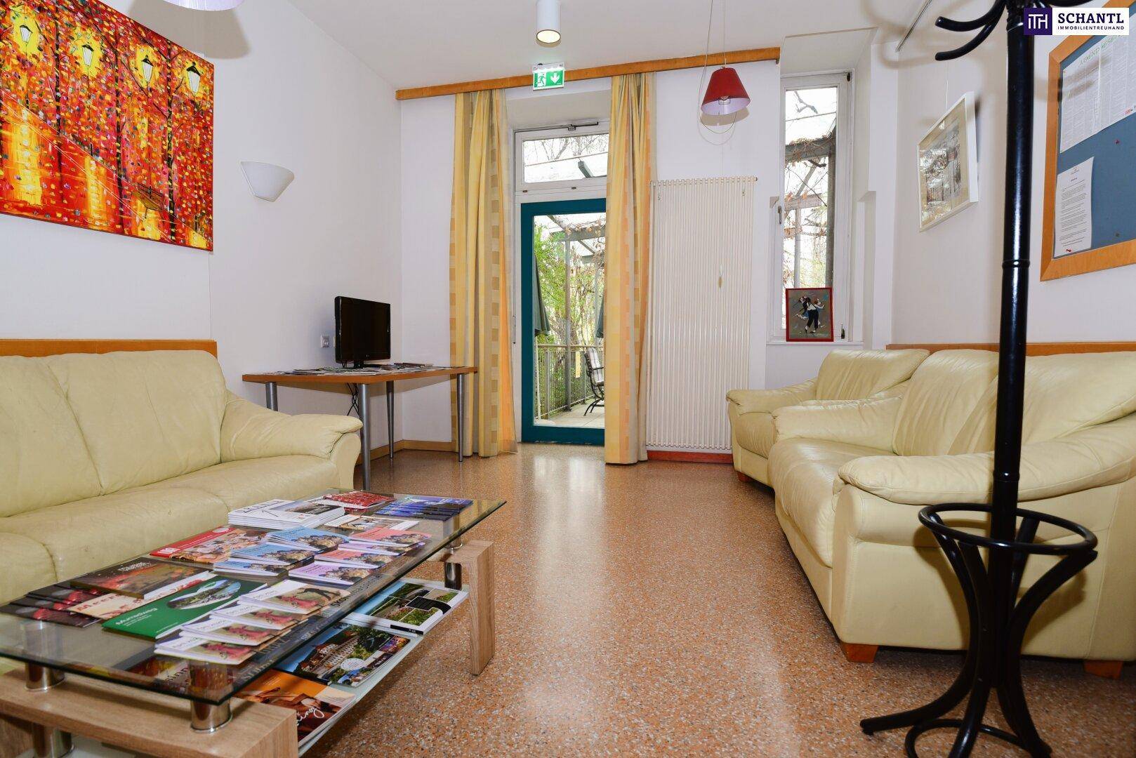 Heller Gemeinschaftsraum mit beigen Sofas, Couchtisch und Zugang zum Außenbereich.