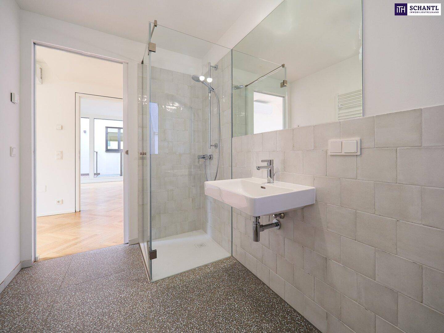 Modernes Badezimmer mit begehbarer Dusche, Waschbecken und großen Wandfliesen.