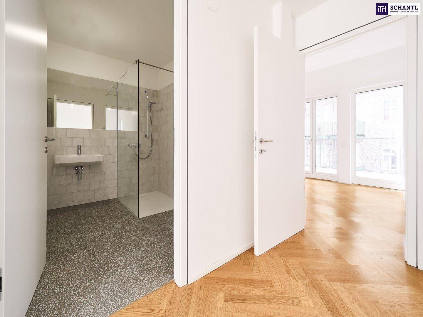 Heller Flur mit Parkettboden, der zu einem modernen Badezimmer und weiteren Räumen führt.