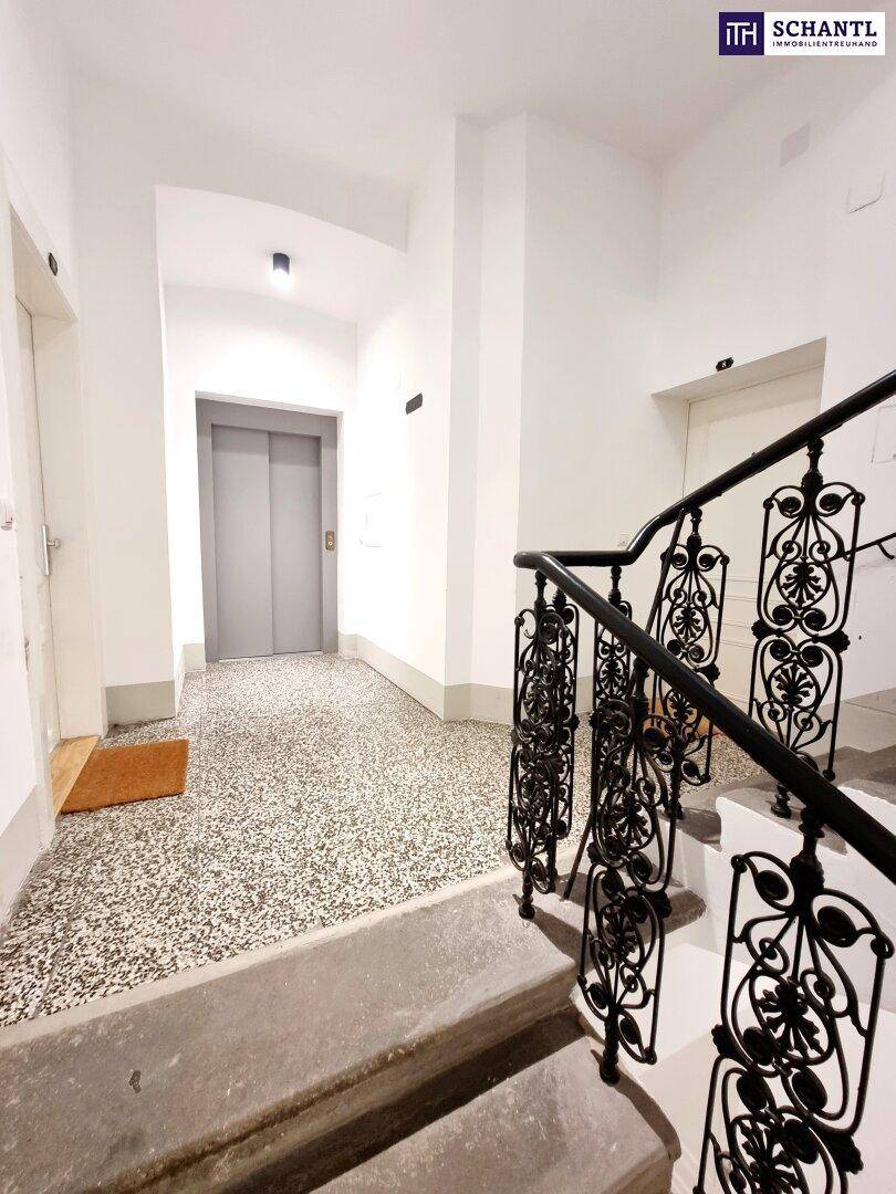Heller Hausflur mit Terrazzoboden, Treppe und Zugang zum Aufzug.