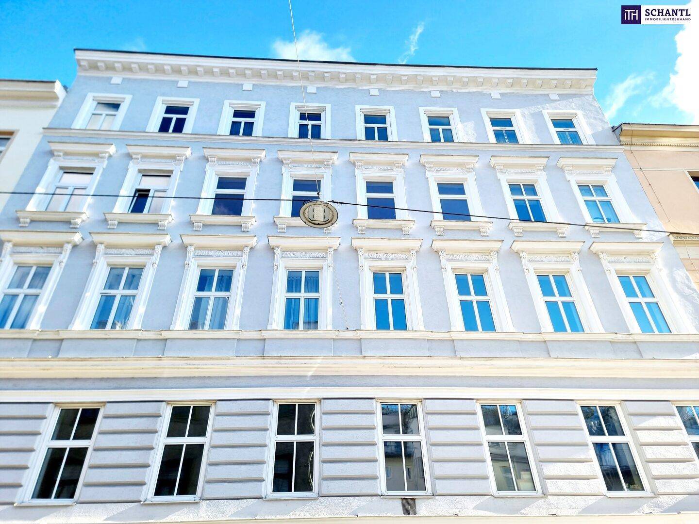 Renovierte Fassade eines Altbaus mit vielen Fenstern und dekorativen Elementen.