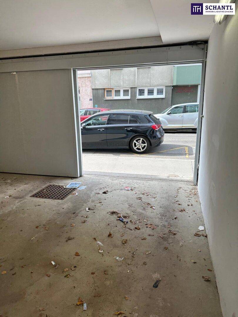 Blick aus einer Tiefgarage auf die Straße mit einem geparkten Auto und umliegenden Gebäuden.