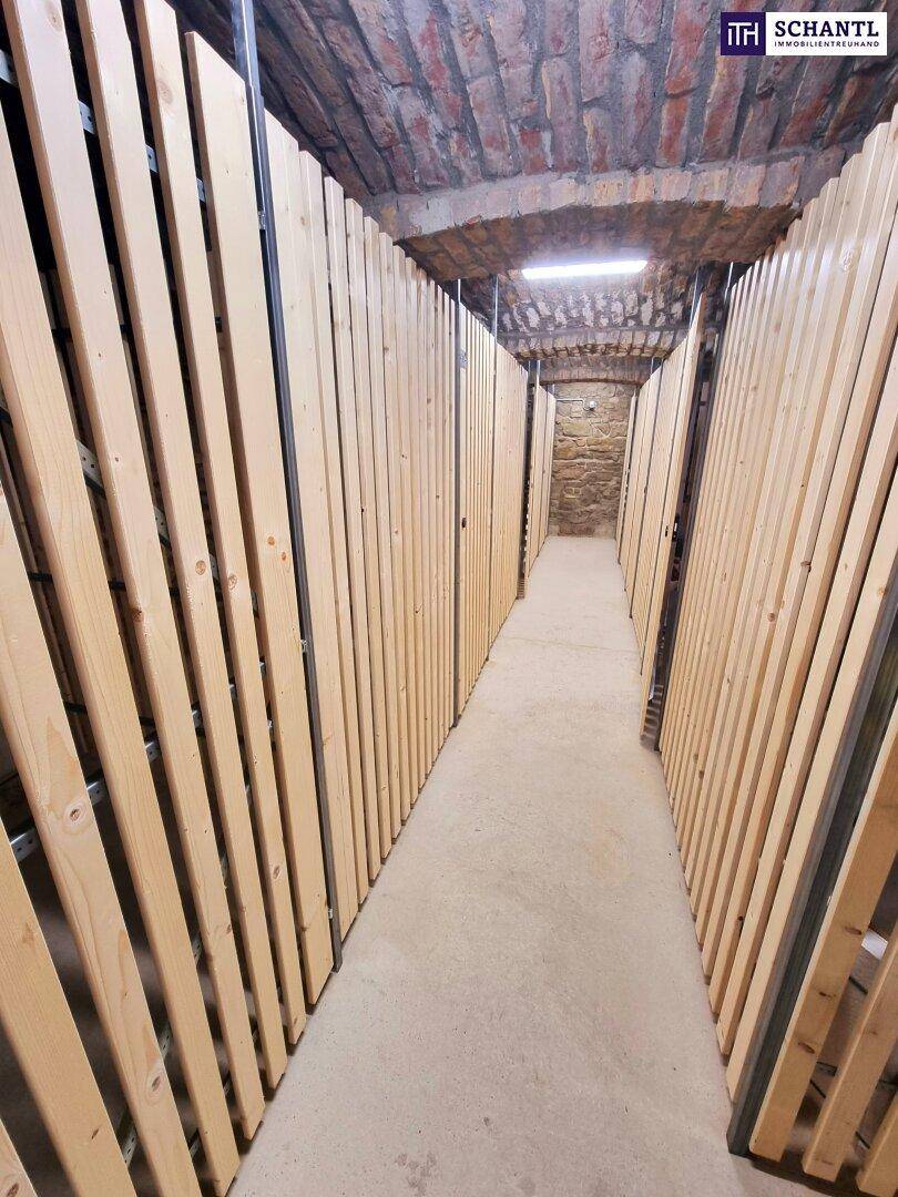 Reihen von Kellerabteilen mit Holzlattenwänden in einem gut erhaltenen Gewölbekeller.