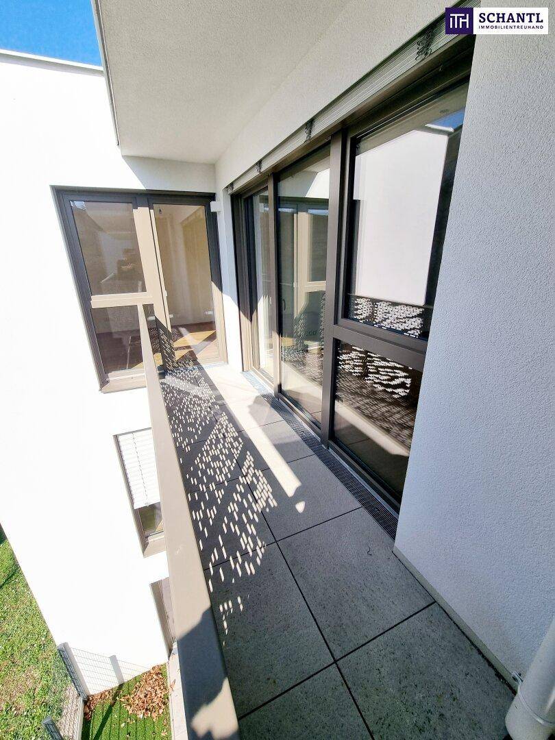 Heller Balkon mit modernen Fliesen und perforiertem Geländer, zugänglich durch große Schiebetüren.
