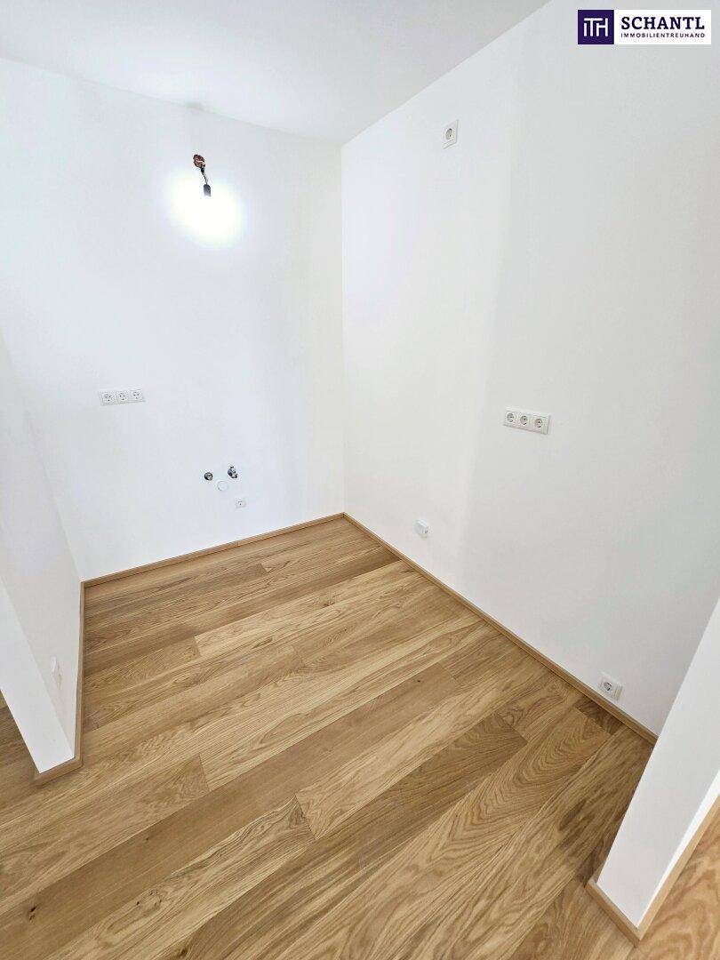 Kleiner, leerer Raum mit Holzparkettboden und Anschlüssen für eine mögliche Küchenzeile.